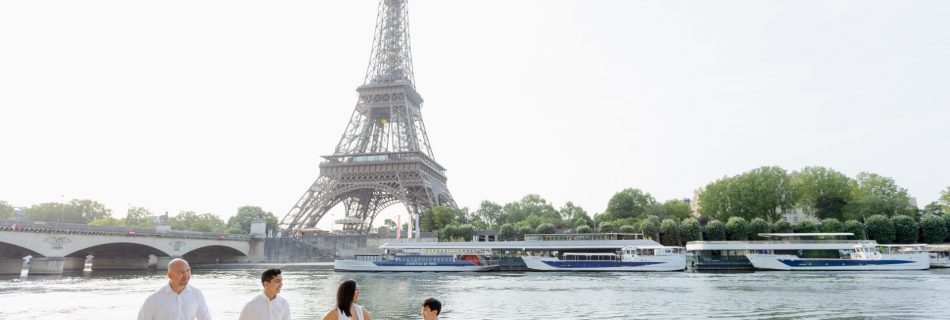 Cute family smiling and walking on the banks of the Seine in front of the Eiffel Tower during a Paris photoshoot